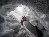 Учёный поднимается из ледяной пещеры возле вершины вулкана Эребус в Антарктиде. (© Alasdair Turner)