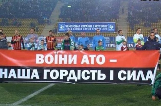 Футболисты приветствовали зрителей на фоне баннера со словами благодарности украинским воинам