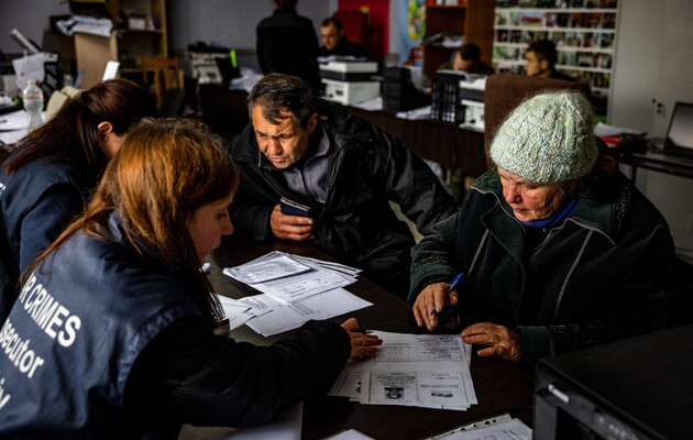 Анна Сухова, 78 лет, заполняет документы для следователей по военным преступлениям, чтобы предоставить свою ДНК для идентификации брата, в городе Изюм, Харьковской области. 4 ноября 2022 года