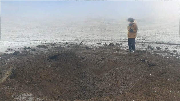 Человек на фоне воронки от снаряда