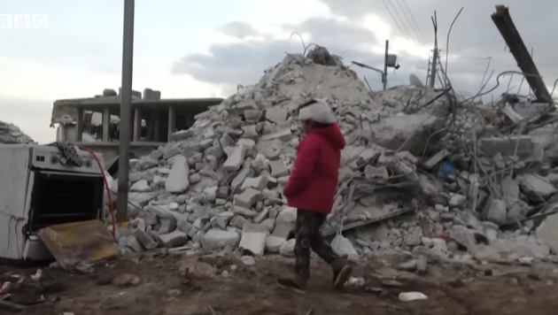 Уцелевший мальчик, вытащенный из-под завалов, показывает место, где его нашли