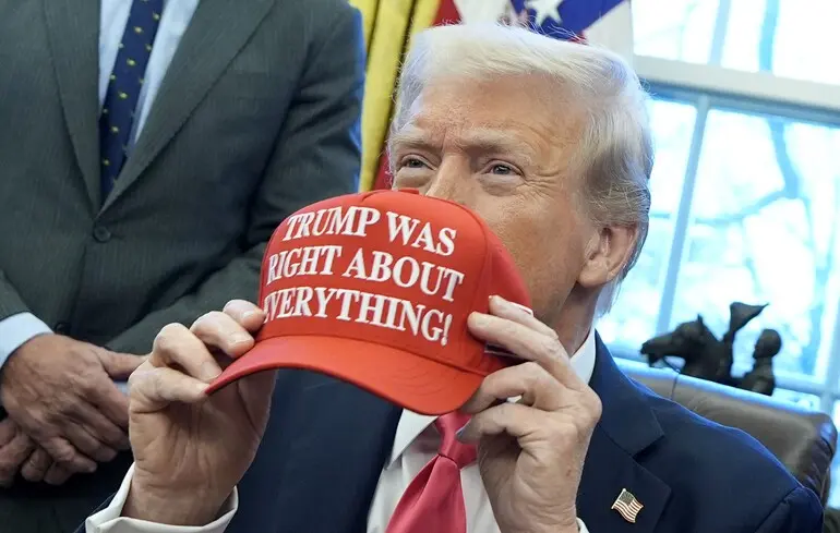Дональд Трамп держит кепку с надписью "Трамп был прав во всем" после подписания указов в Овальном кабинете Белого дома / 25 февраля 2025 года