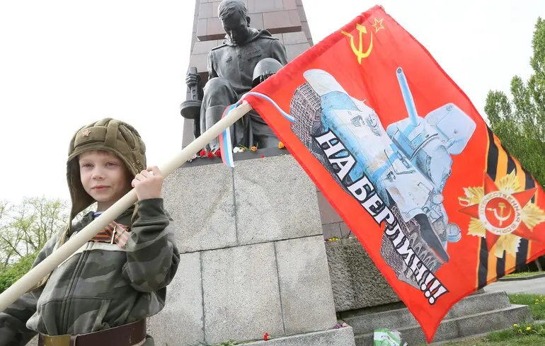 Дитина з Росії тримає прапор, стоячи перед радянським монументом у Трептов-парку в Берліні / 8 травня 2015 року