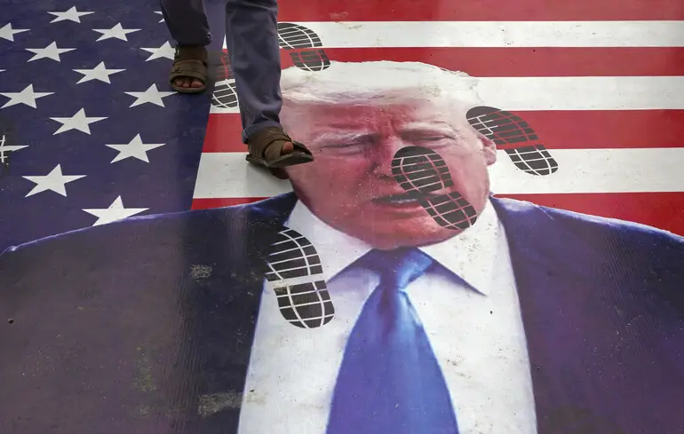 Протестувальник у Пакистані йде по зображенню Дональда Трампа під час демонстрації проти США та Ізраїлю / 22 червня 2025 року