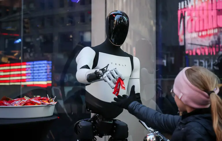 Робот Tesla Optimus раздает конфеты перед биржей Nasdaq MarketSite, Нью-Йорк, США / 27 октября 2025 года