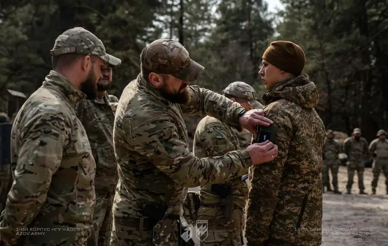Інструктор 12-ї бригади спеціального призначення «Азов» надягає нарукавний знак на військового під час підготовки