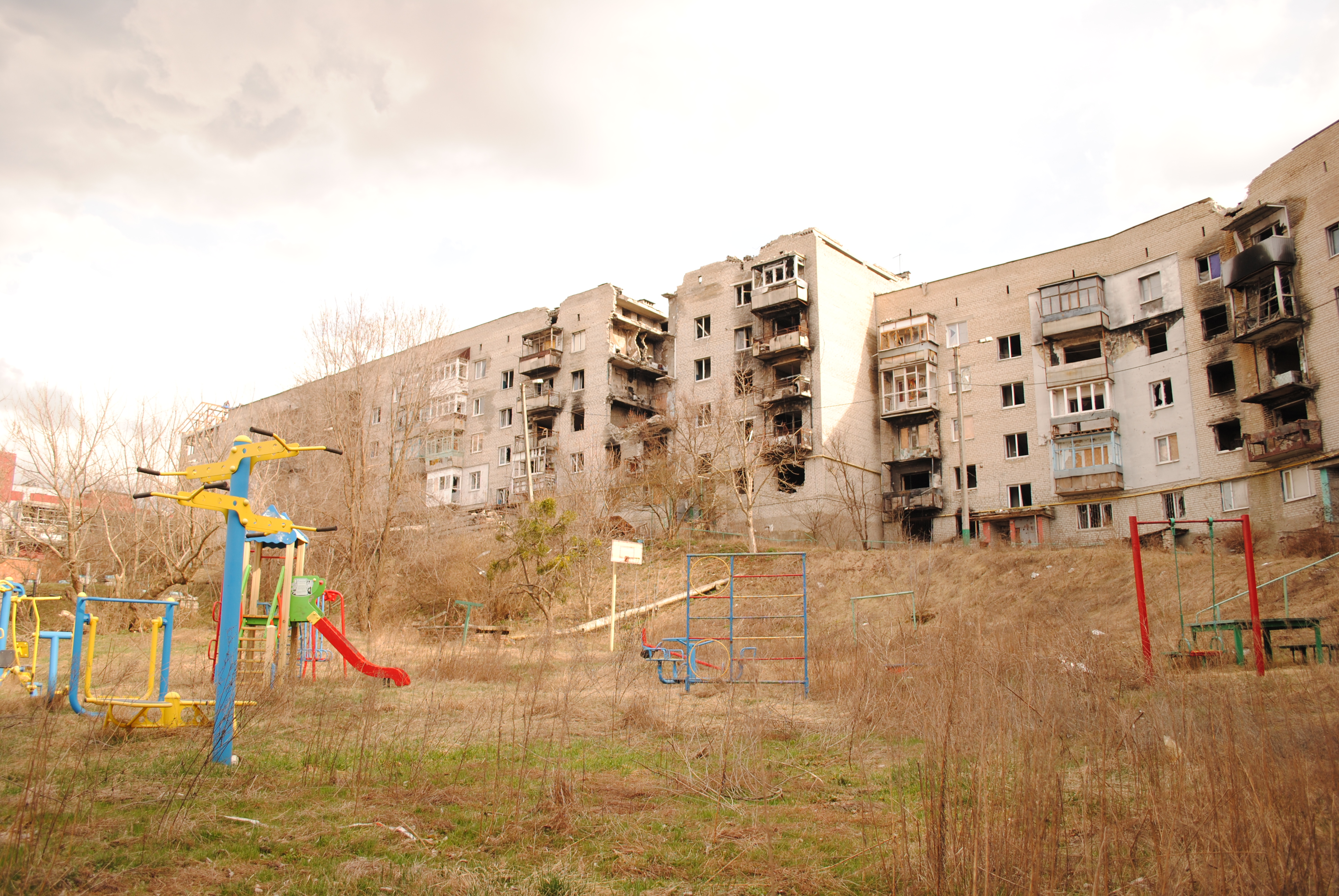Такой вид у жилых кварталов в центральной части Изюма — выжженные изнутри дома, заросшие сорняками детские площадки