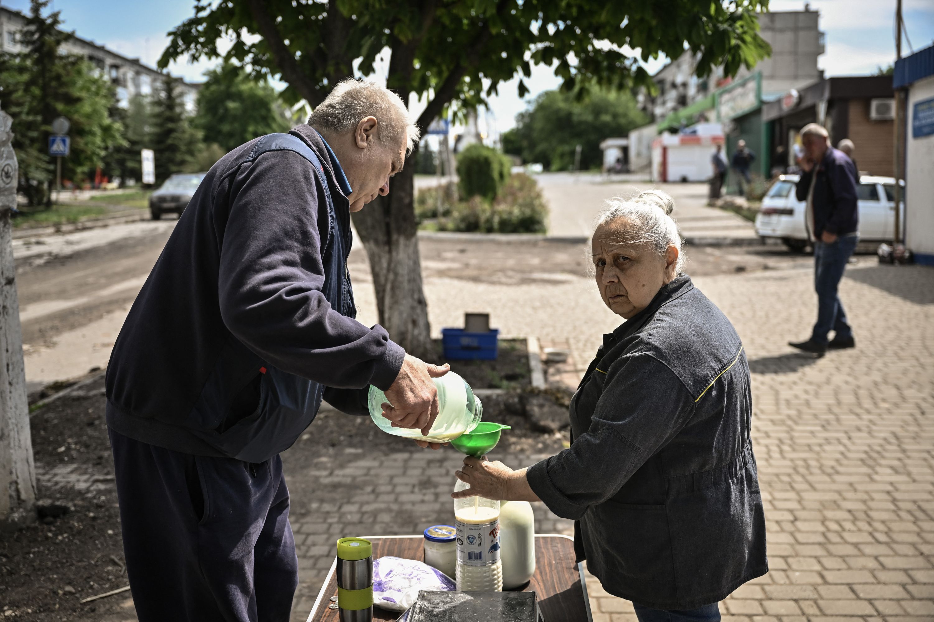Женщина покупает молоко у уличного торговца в городе Соледар в восточном регионе Украины Донбассе 28 мая 2022 года. 94-й день вторжения России в Украину.
