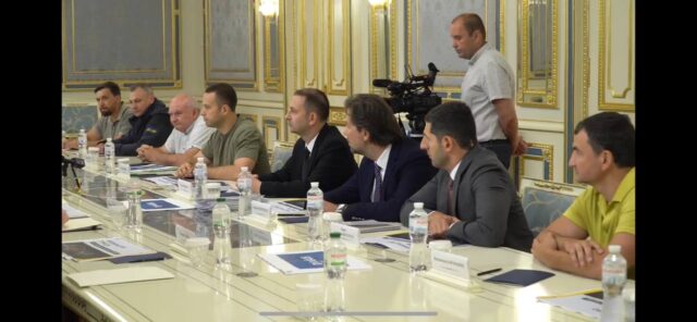 Скірншот відео. Зліва направо: замдиректора «Автомагістралі-Південь» Валерій Вакарчук та власник фірми Олександр Бойко, директор «Автостради» Анатолій Вакар та власник фірми Максим Шкіль, три представники турецького бізнесу з керівником «Онур конструкціон інтернешнл» Емре Караахметоглу, власник «Рудомайну» Костянтин Караманіц (у жовтій футболці).