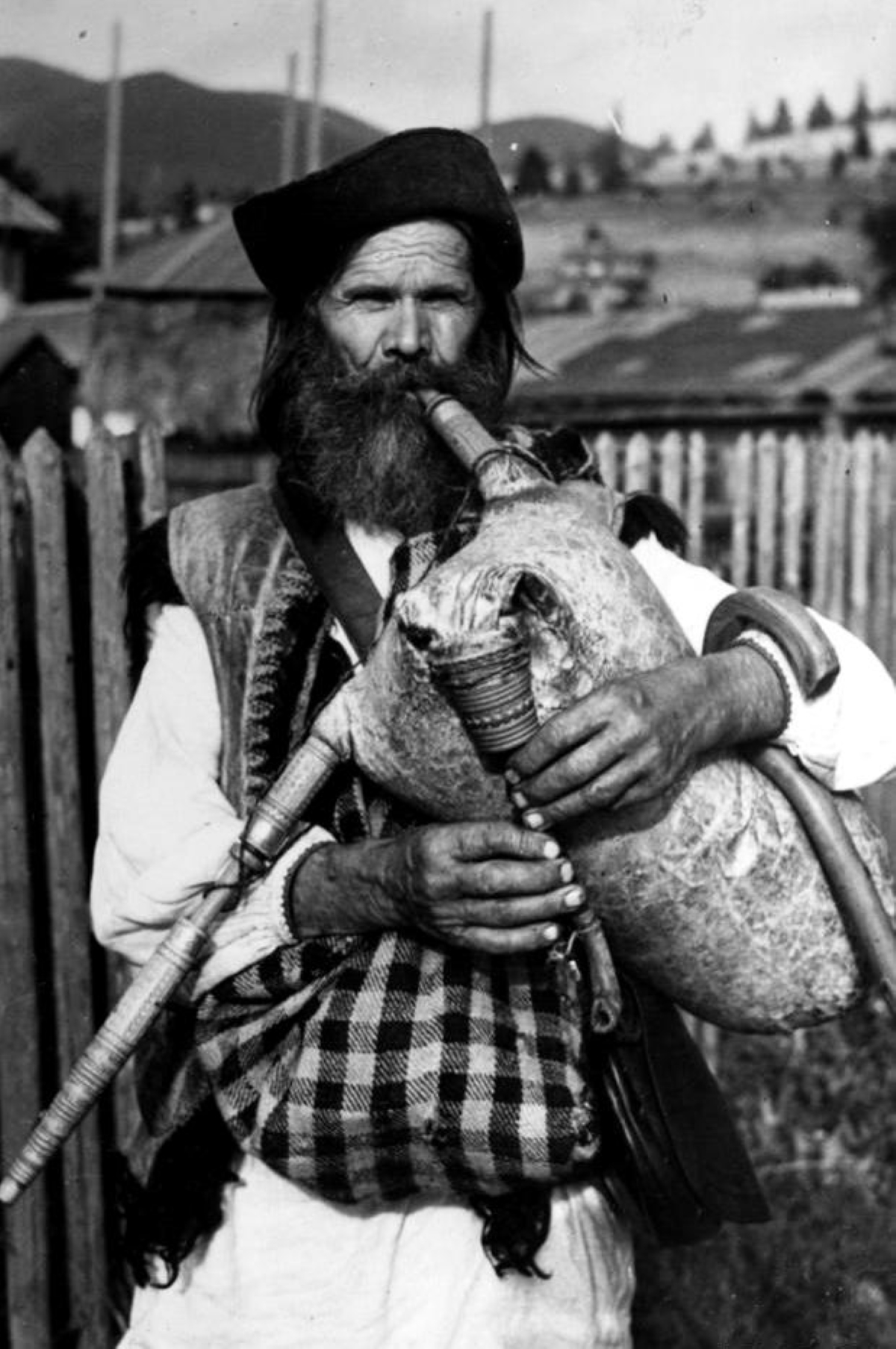 Николай Сеньковский. Дударь Козьма Михайлюк с гуцульской козой — волынкой, изготовленной из козьей кожи, отсюда и народное название инструмента. Мох покрыт клетчатой ​​тканью, хорошо видна вдувка, мелодичная трубка и бурдон. Косов, 1931г.