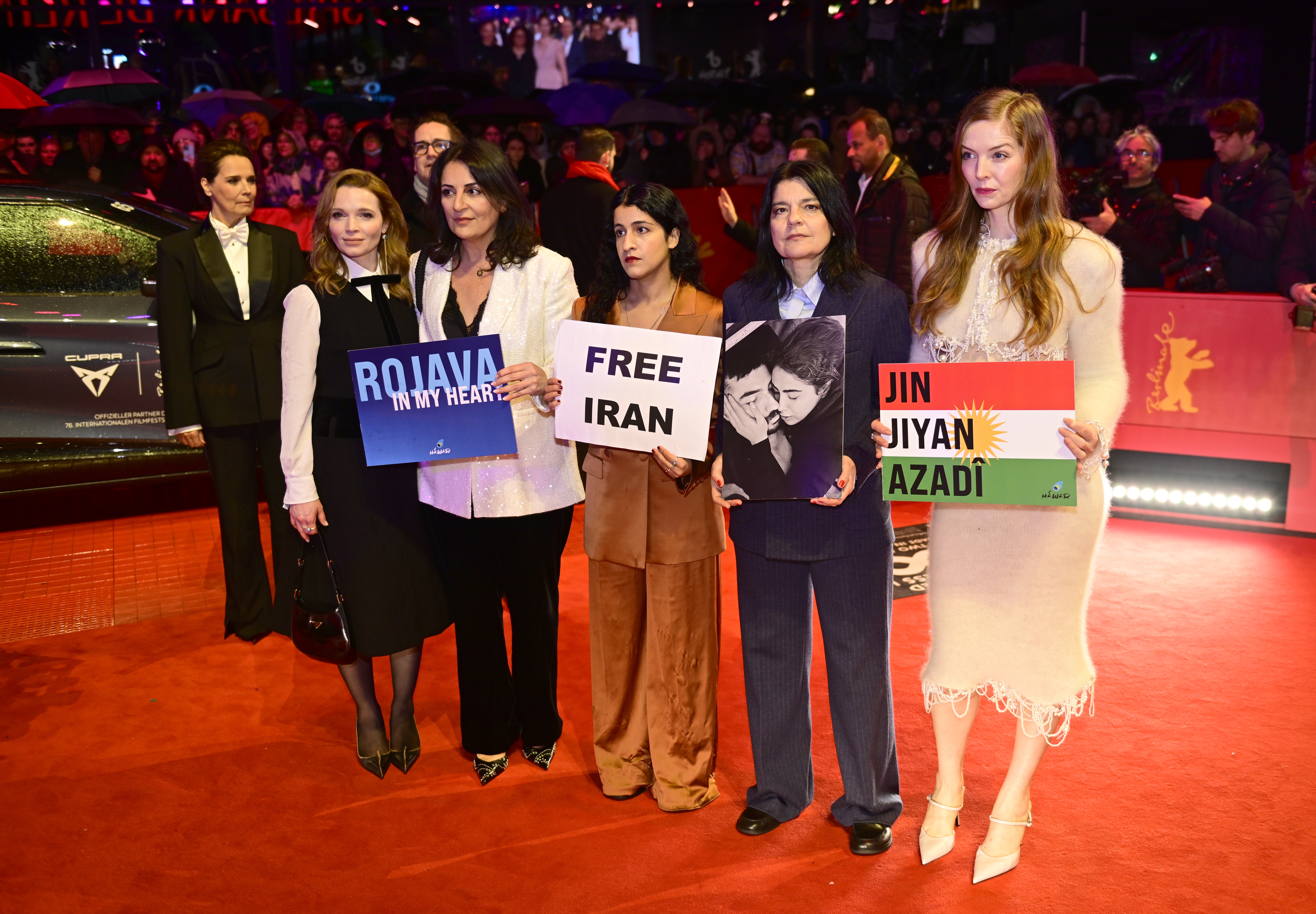 Гості церемонії відкриття Берлінале-2026 тримають плакати 'Free Iran' та 'Rojava'. Гості церемонії відкриття Берлінале-2026 тримають плакати 'Free Iran' та 'Rojava'.