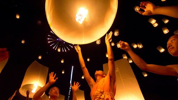 Монахи-паломники запускают в небо фонарики у стен храма Song Pee Nong, Таиланд